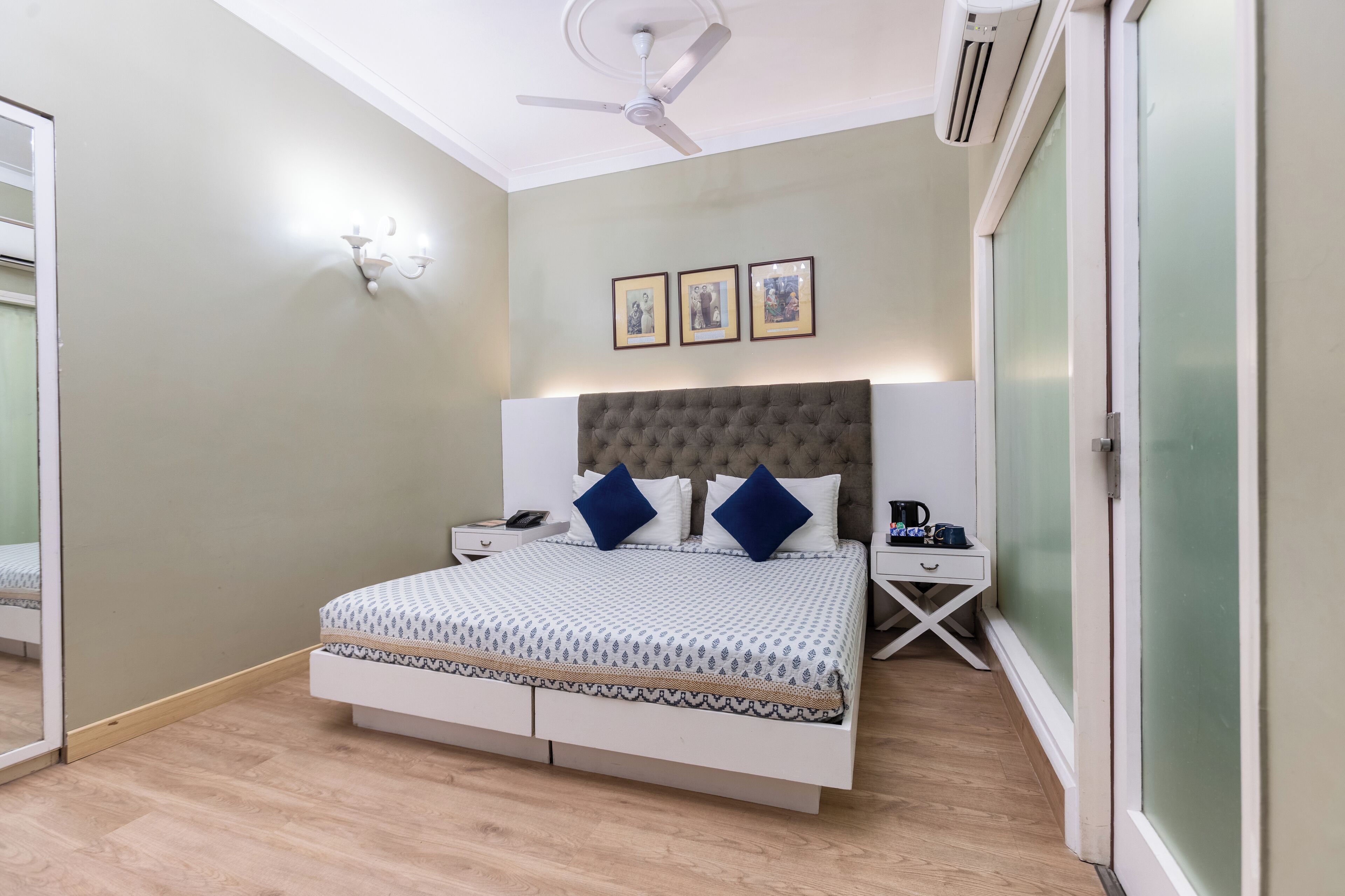 A bedroom with a bed, bedside tables, a ceiling fan, and framed pictures on the wall.