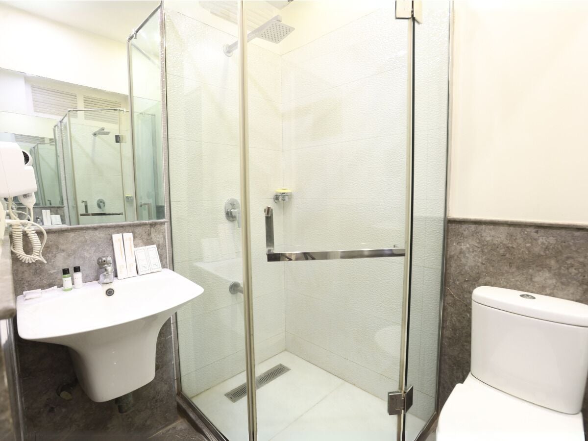 A modern bathroom with a glass-enclosed shower, a white sink, and a toilet.