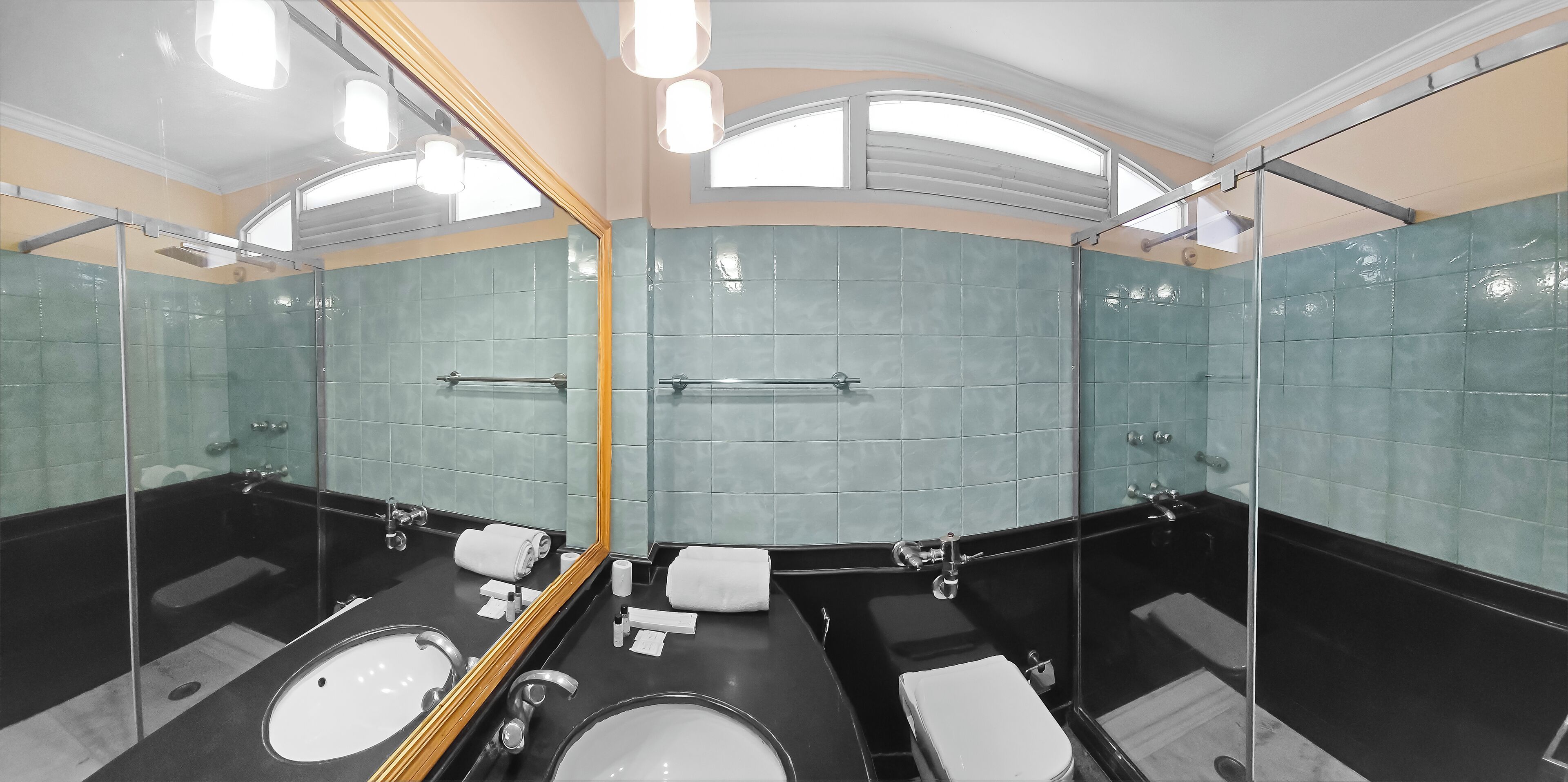 A modern bathroom with a large mirror, two sinks, a bathtub, and a shower.