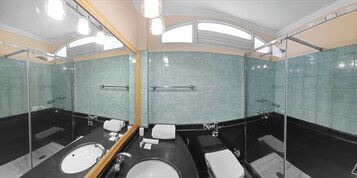 A modern bathroom with a large mirror, two sinks, a bathtub, and a shower.