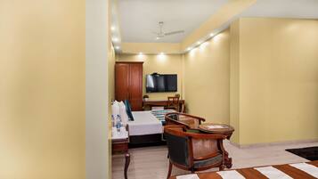 A hotel room with a bed, a desk, a chair, a television, and a ceiling fan.