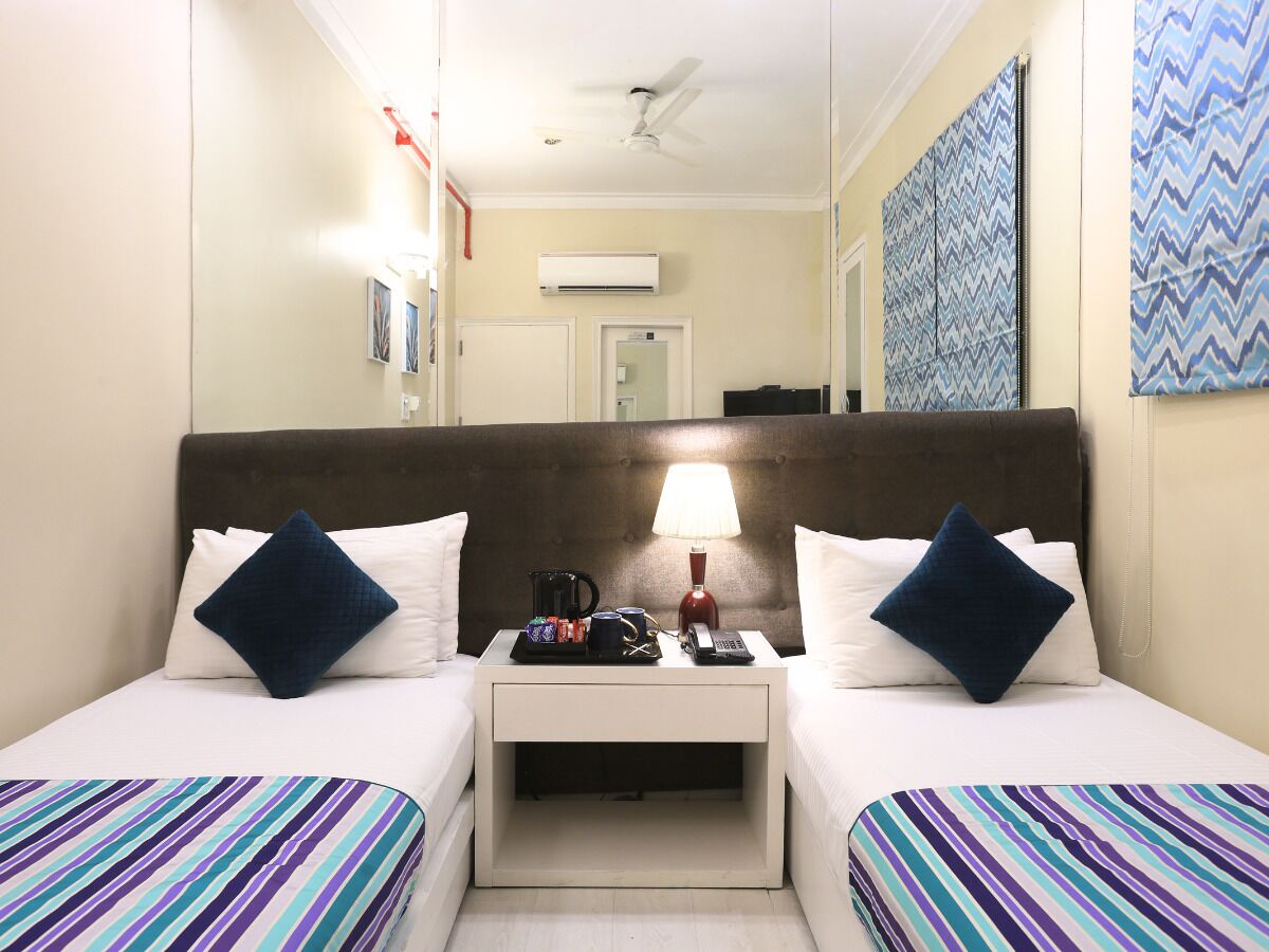 Habitación de hotel con dos camas, una mesita de noche con lámpara, cafetera y teléfono.