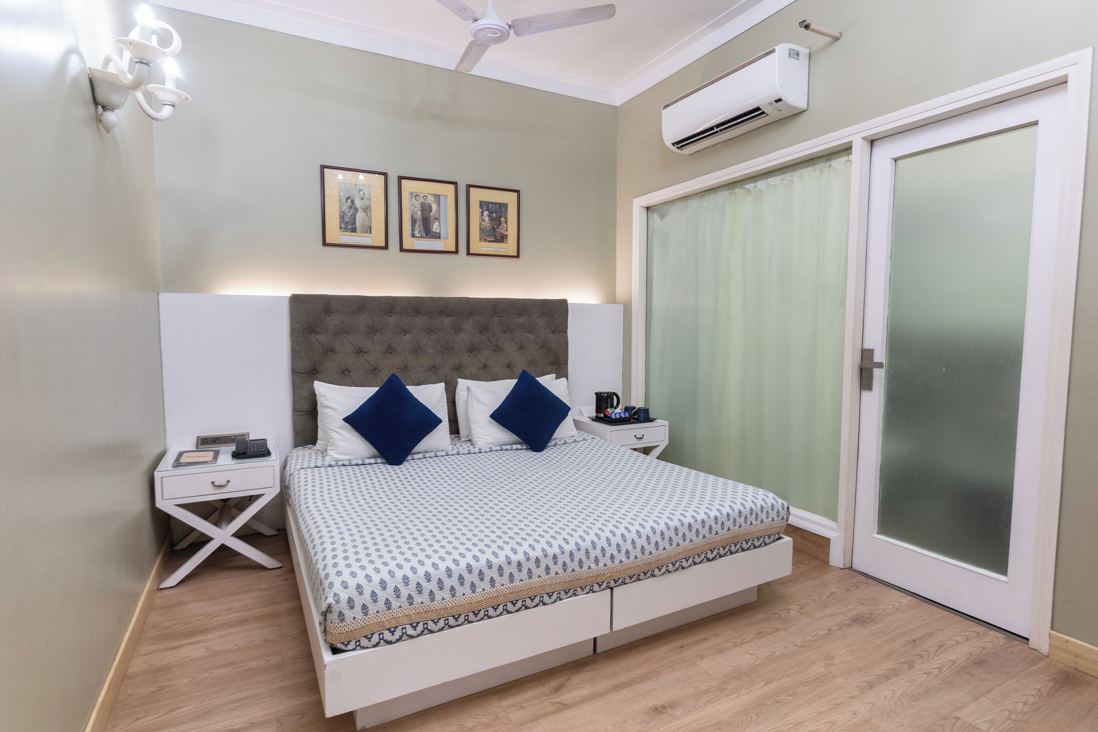 A bedroom with a bed, bedside tables, a ceiling fan, an air conditioning unit, and a sliding glass door.