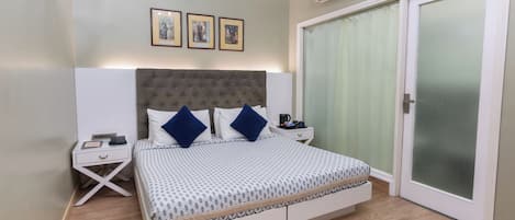 A bedroom with a bed, bedside tables, a ceiling fan, an air conditioning unit, and a sliding glass door.