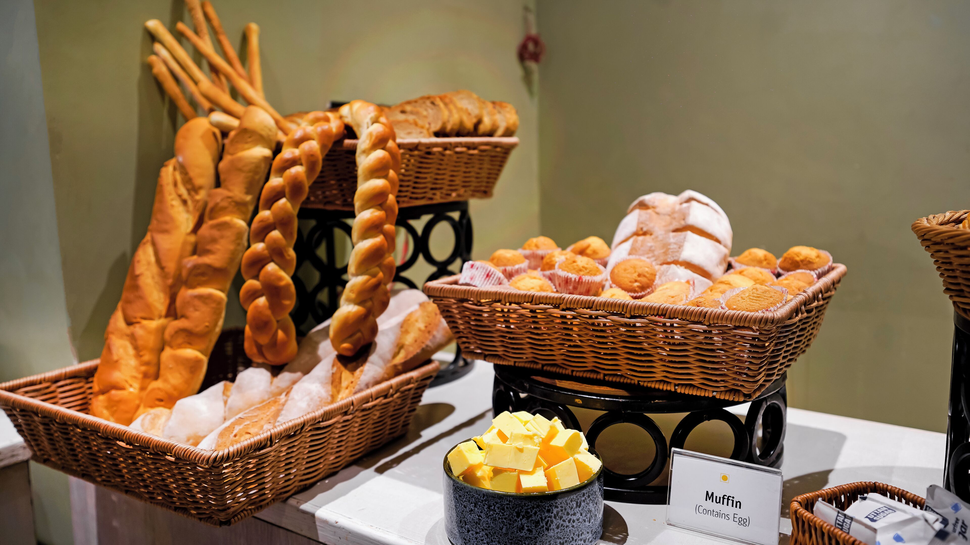 A display of various baked goods including bread, muffins, and a container of butter.