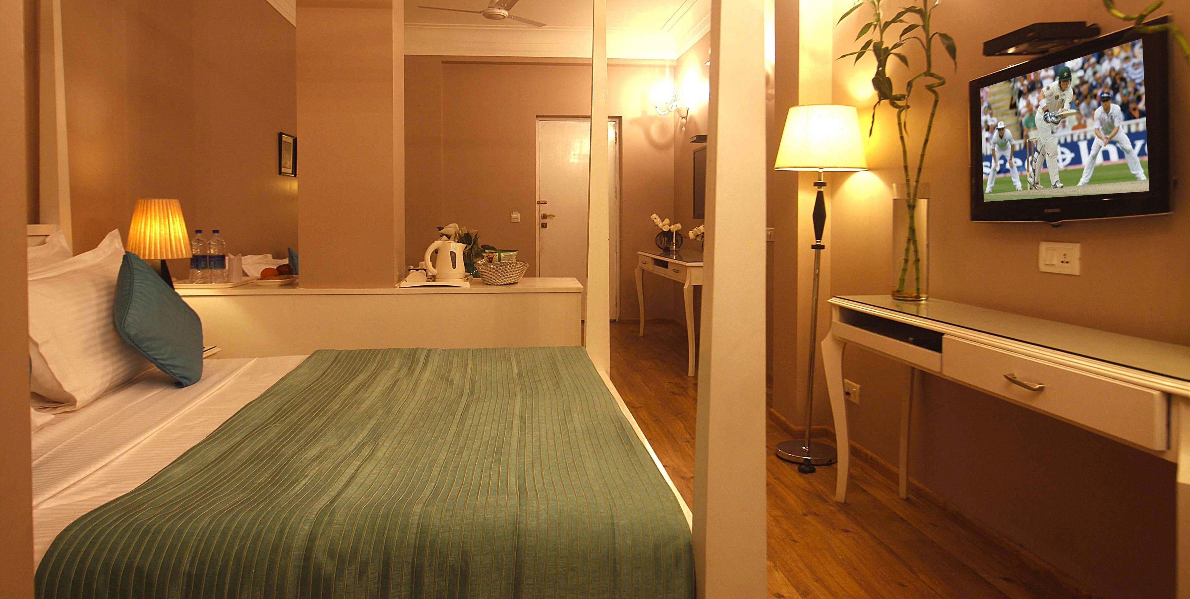 Een hotelkamer met een bed, een bureau, een televisietoestel en een badkamer in de achtergrond.