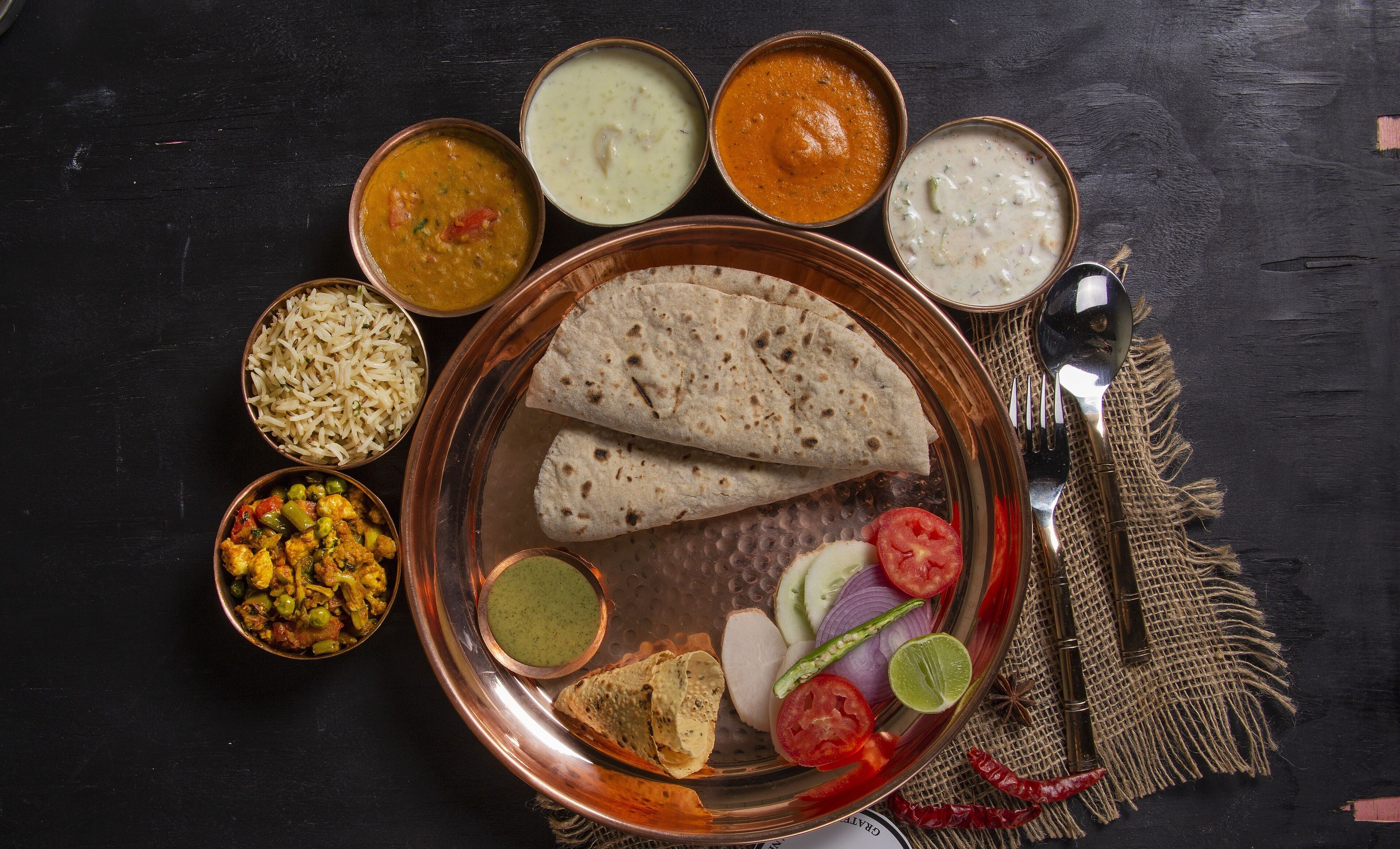 A traditional Indian meal with various dishes and a plate of flatbreads.