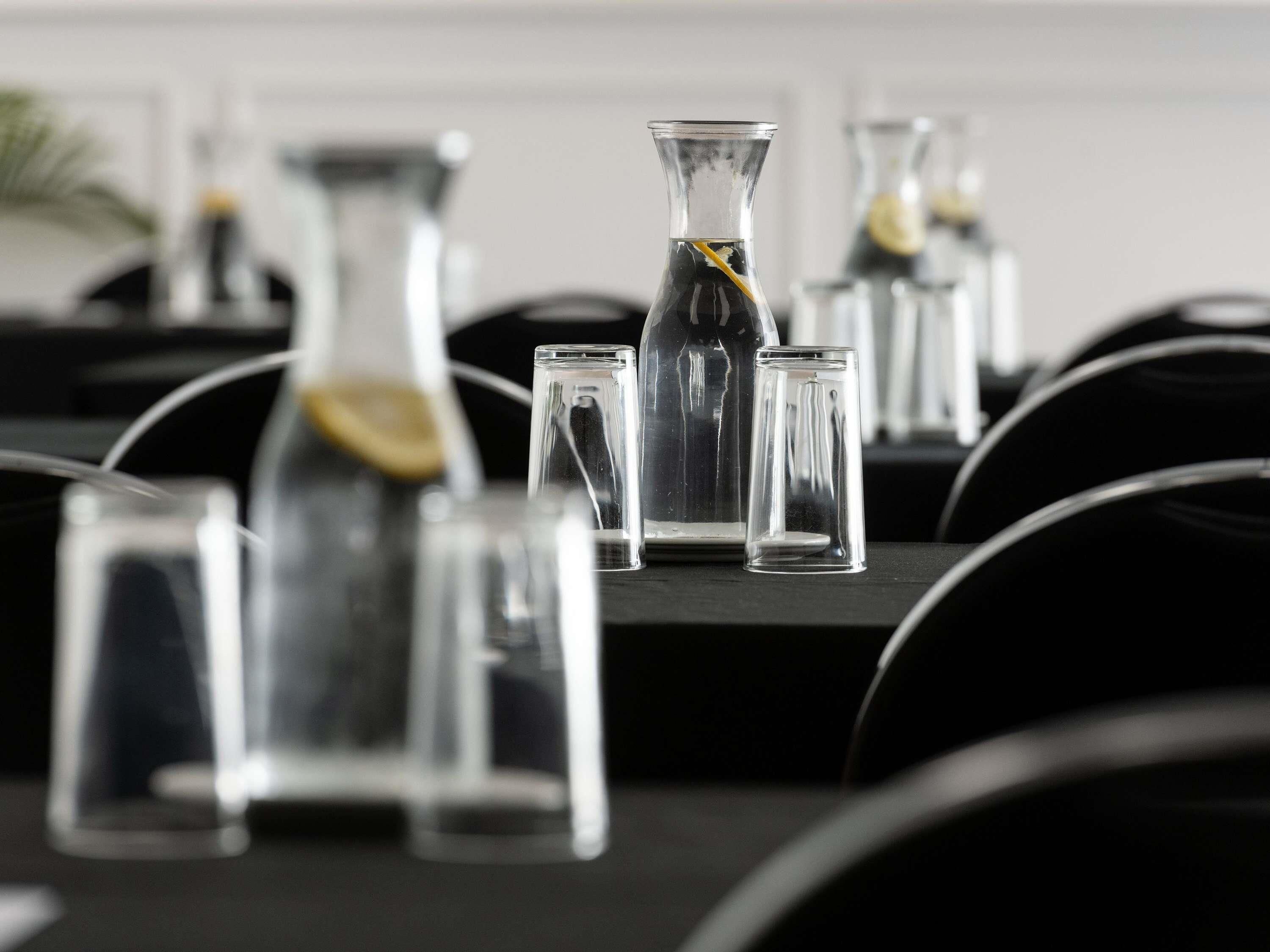 Una fila de botellas y vasos de vidrio transparentes sobre una mesa, probablemente para bebidas.