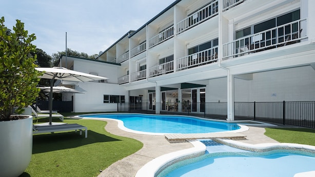 A modern building with a swimming pool, outdoor seating, and a well-maintained lawn. - Mercure Tauranga (Tauranga)