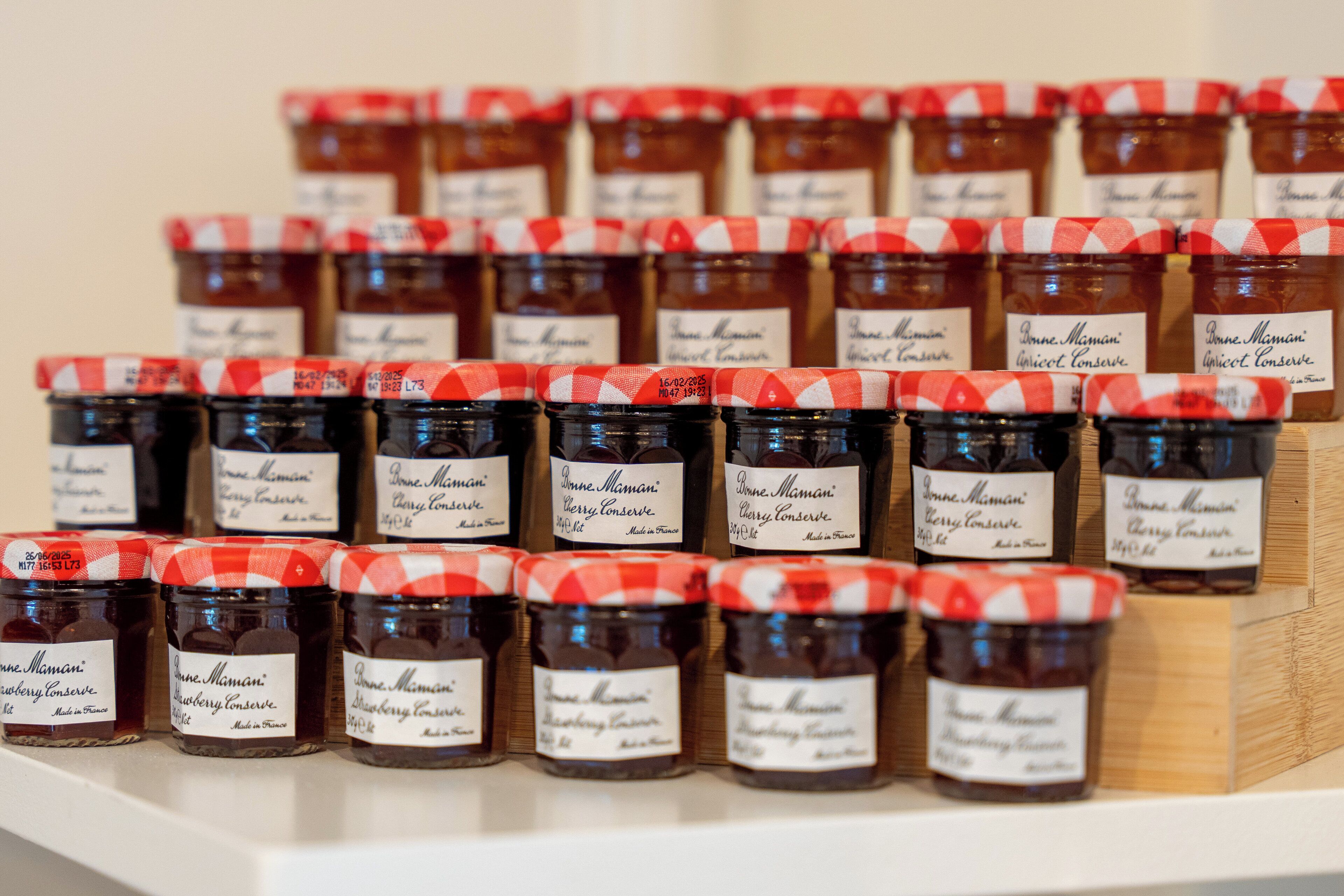 Plusieurs pots de confitures de la marque « Bonne Maman » sont alignés sur une étagère.
