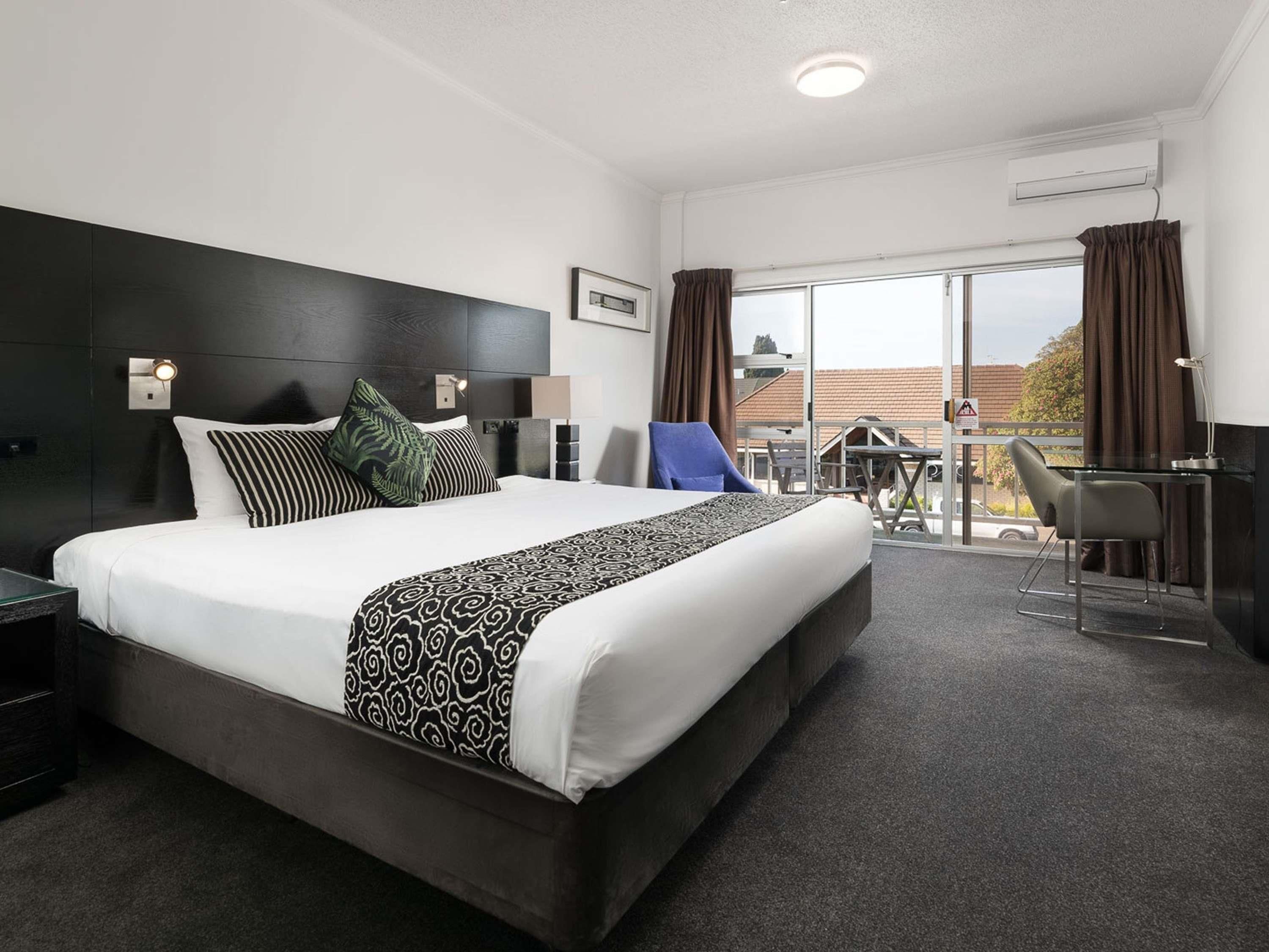 Una habitación de hotel con una cama grande, un escritorio y un balcón con vistas.