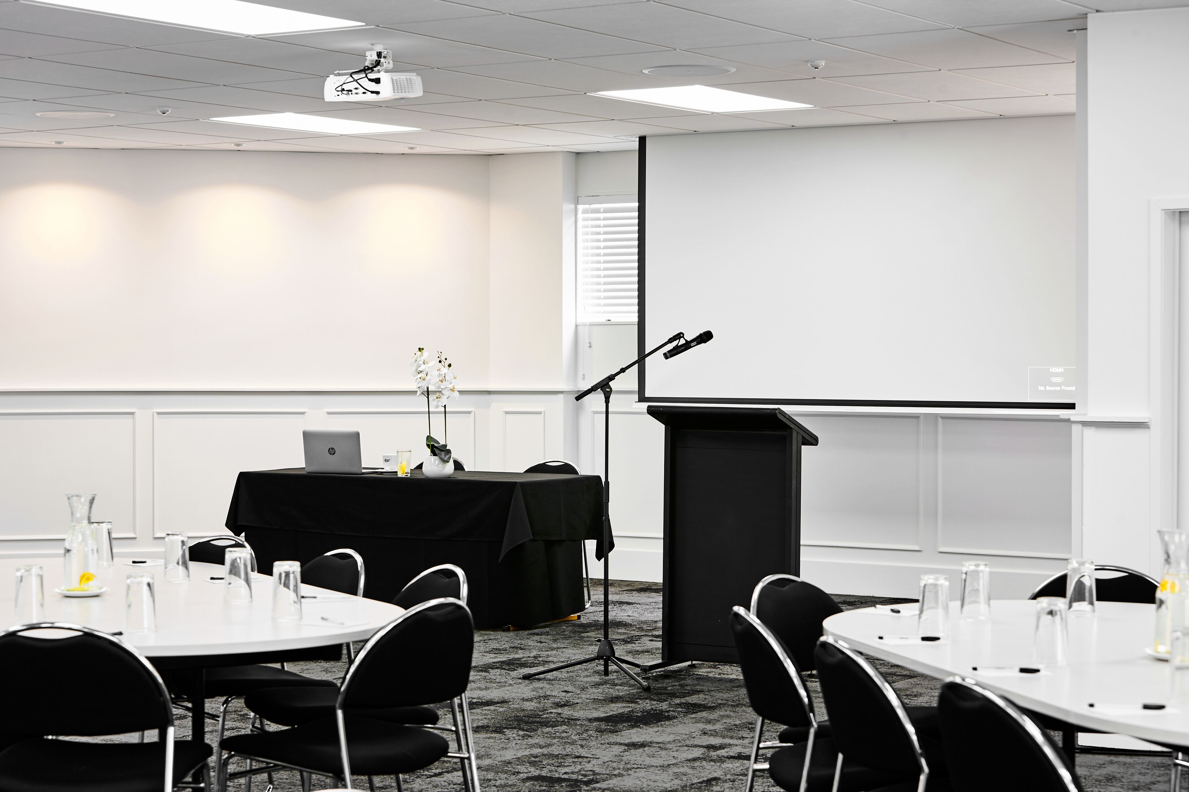 A conference room with a projector, a podium, and a laptop on a table.