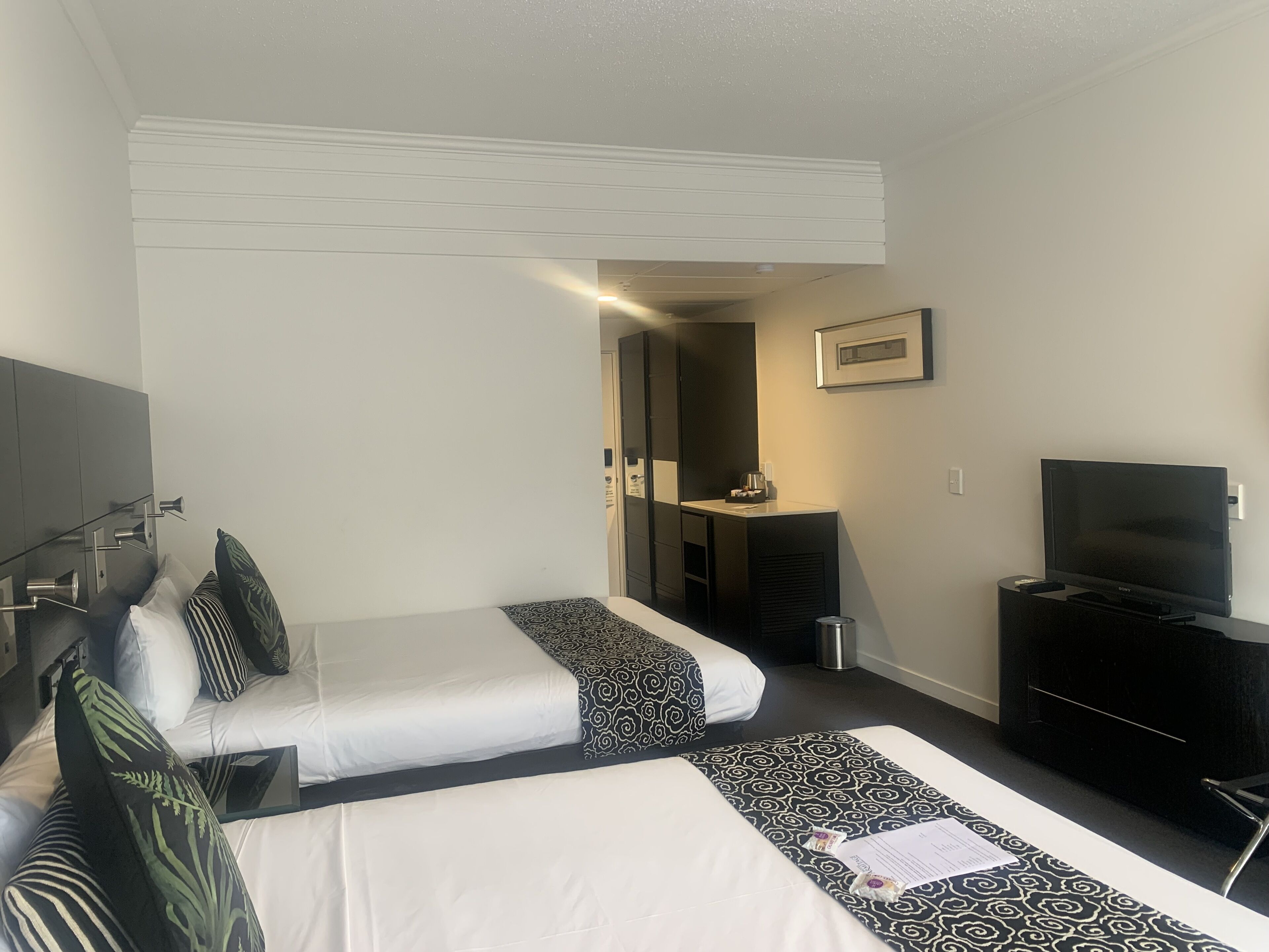 Une chambre d’hôtel avec deux lits, une télévision, un bureau et un miroir.