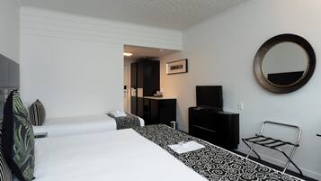 Una habitación de hotel con dos camas, un televisor negro, un espejo y una pequeña mesa.