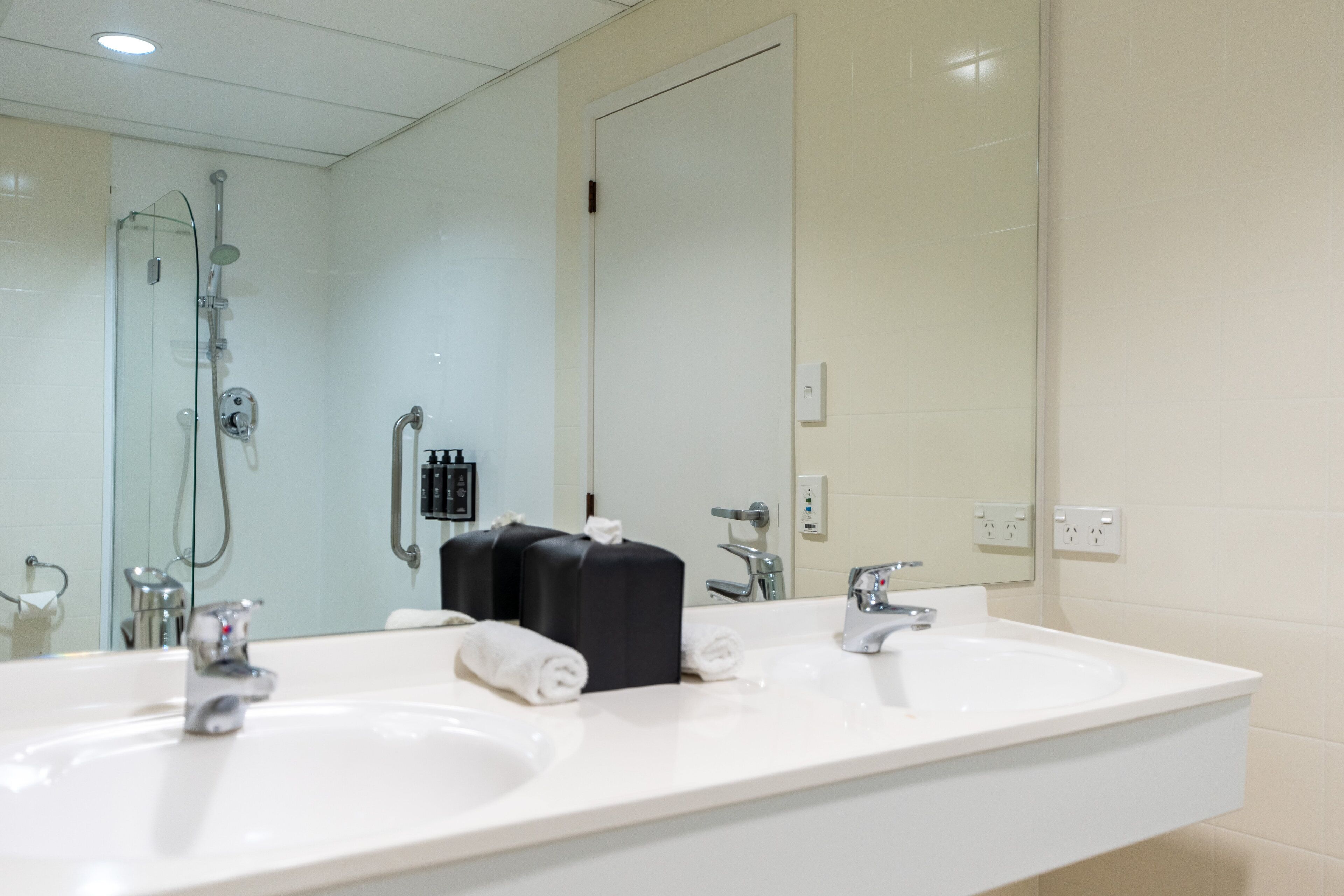 Une salle de bain moderne avec deux lavabos, un grand miroir et une douche à l’italienne.