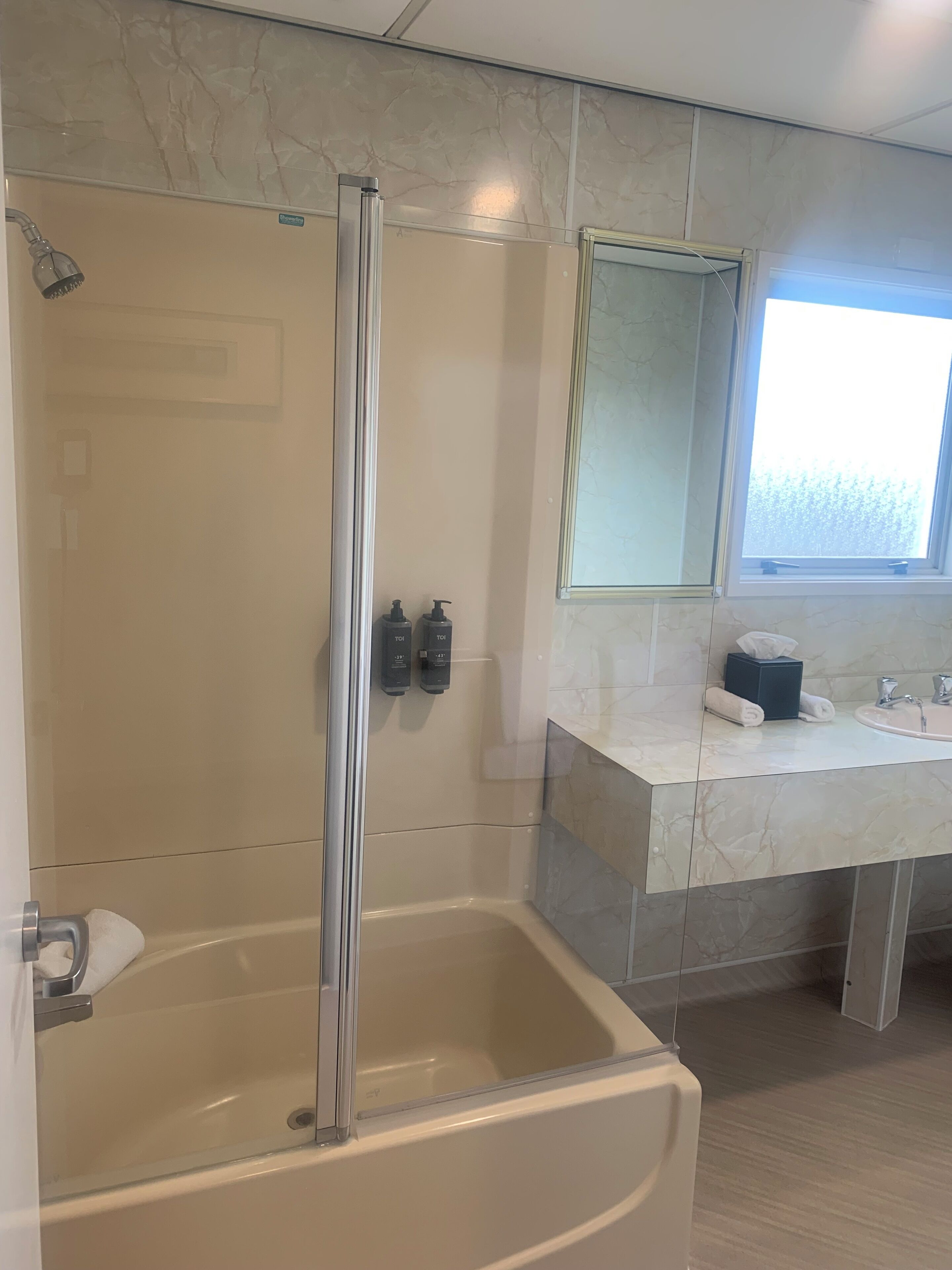 Ein modernes Badezimmer mit einer gläsernen Duschkabine, einer großzügigen Badewanne und einem Waschtisch mit Spiegel.
