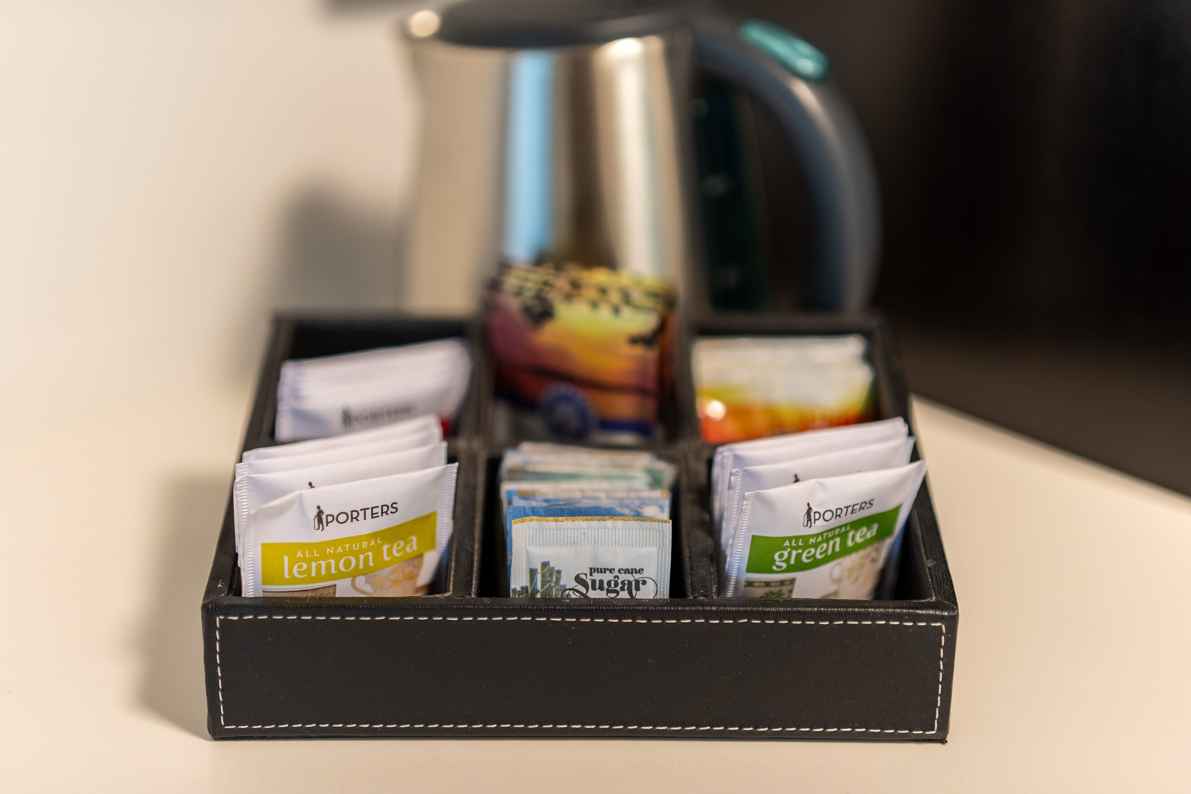 A black leather box containing tea packets labeled 'Lemon Tea' and 'Green Tea'.