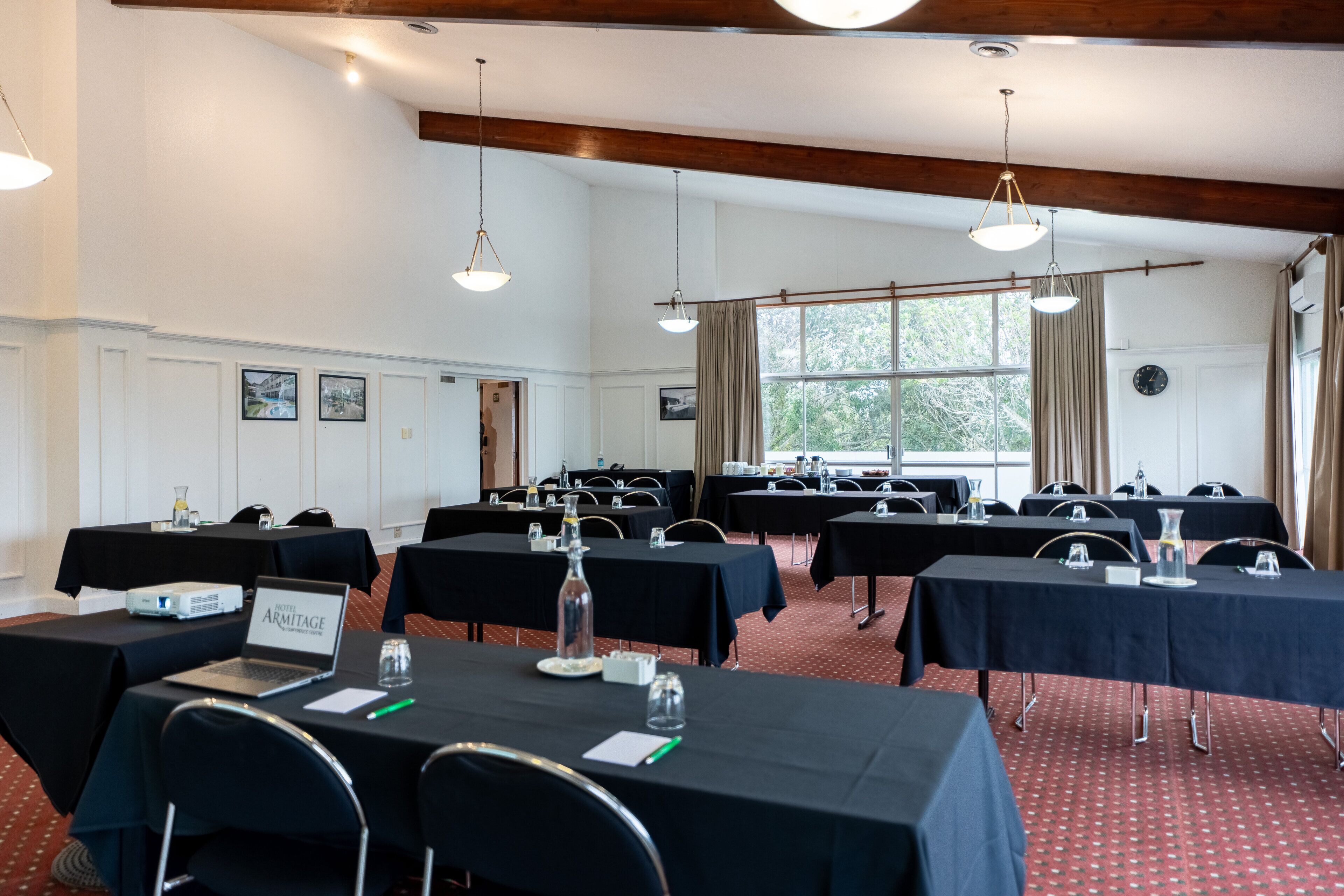 Un salón de conferencias con mesas, sillas y una computadora portátil.