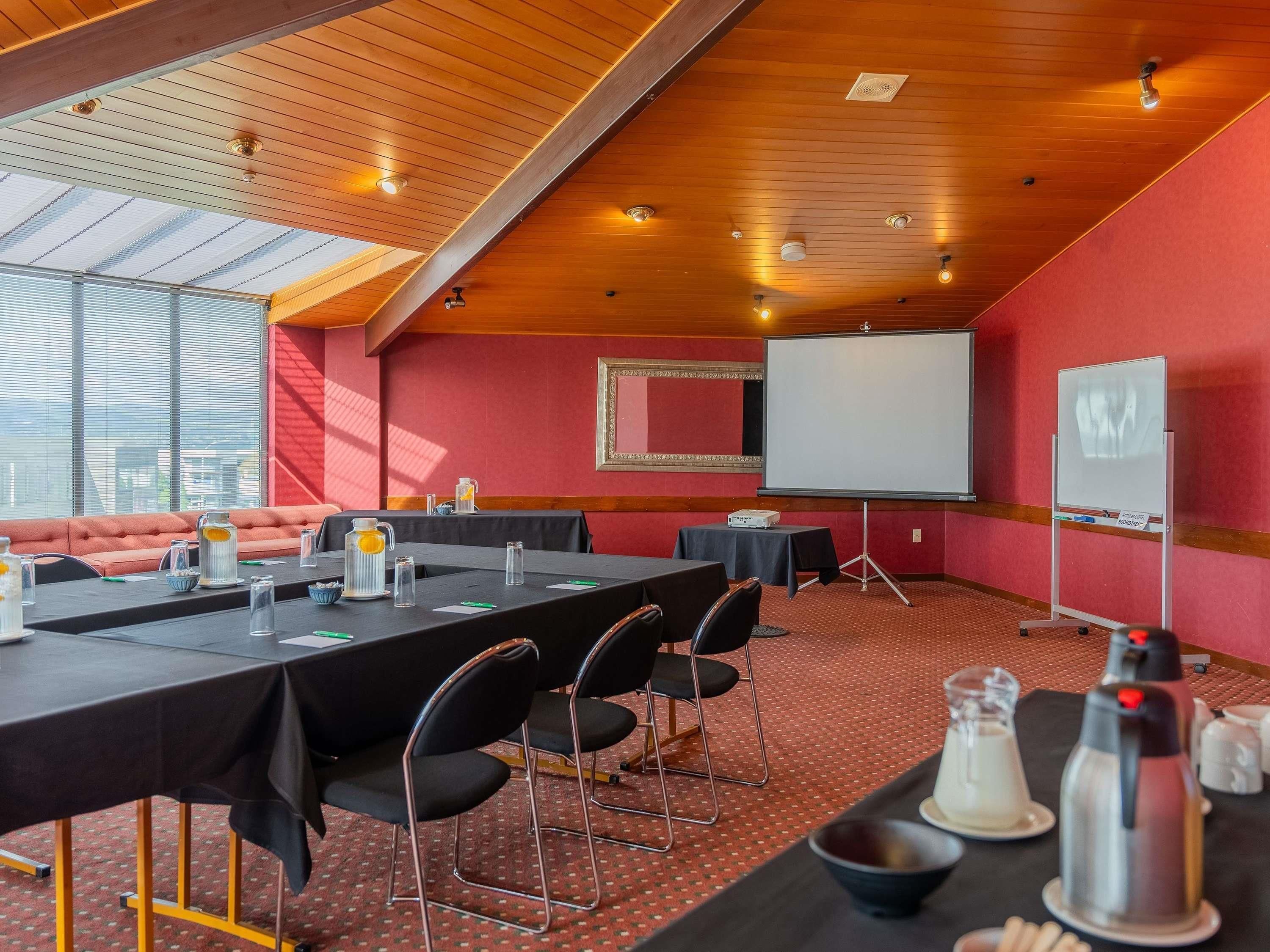 A conference room with a long table, chairs, a whiteboard, and a projector.