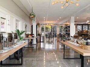 A spacious dining area with polished granite floors, long communal tables, and modern pendant lighting. - Mercure Tauranga (Tauranga)