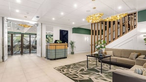 A modern lobby with a reception desk, a staircase, a sofa, and a coffee table. - Mercure Tauranga (Tauranga)