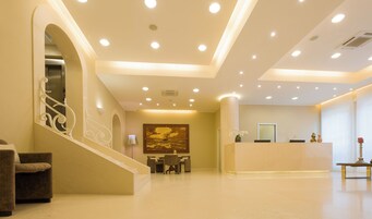 Hall d'albergo con reception, area salotto e scala.