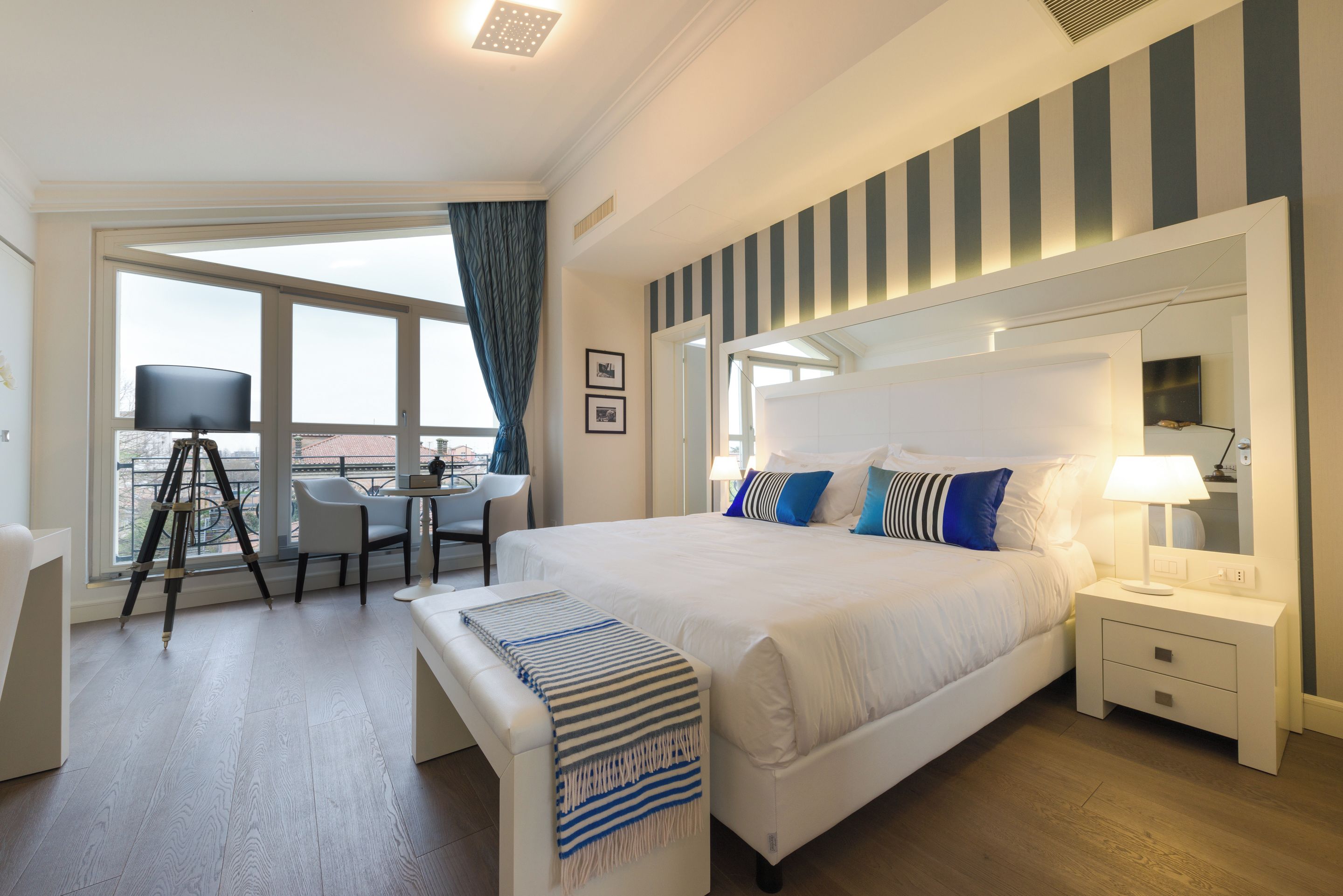 Habitación de hotel con una cama grande, un escritorio con una silla, vistas al balcón y un diseño moderno.