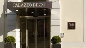A entrada do Palazzo Bezza, com uma porta em arco moderna e um letreiro acima.