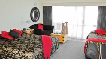 A hotel room with two beds, a chair, a small table, and a mirror on the wall.