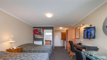 Une chambre d’hôtel avec deux lits, un bureau, une chaise, une télévision et un miroir.