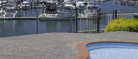 Una marina con barche ormeggiate, una piscina e vista su case sullo sfondo.