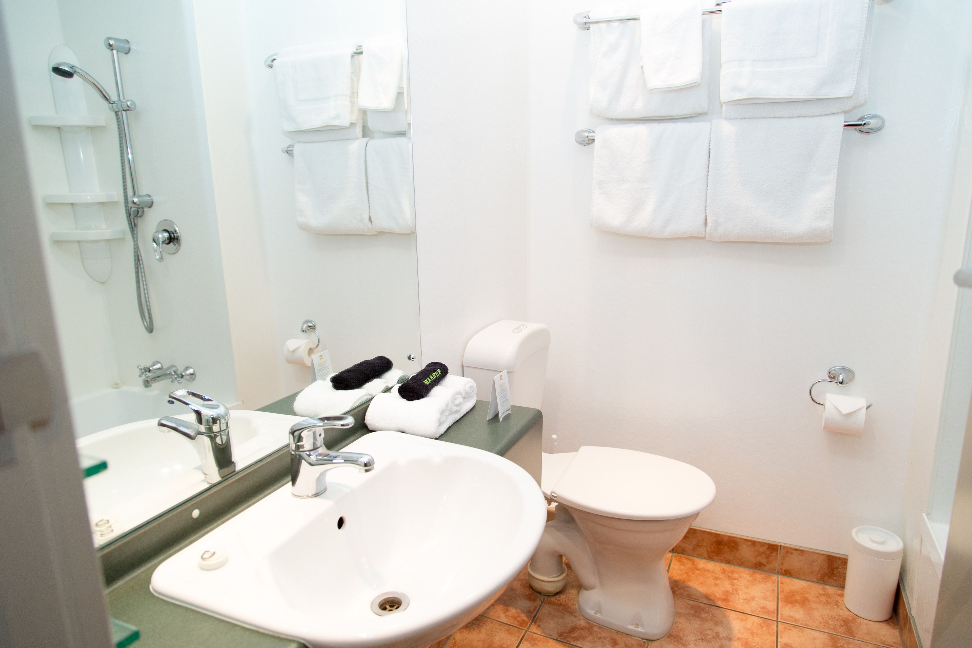 A modern bathroom with a sink, mirror, toilet, and towel rack.