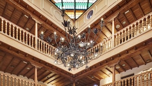 Eine imposante Lobby mit hoher Holzbalkendecke, einem großen Kronleuchter und einer zentralen Fontäne.