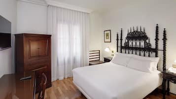 Una habitación de hotel con una cama grande, muebles de madera, un televisor y un cabecero decorativo.