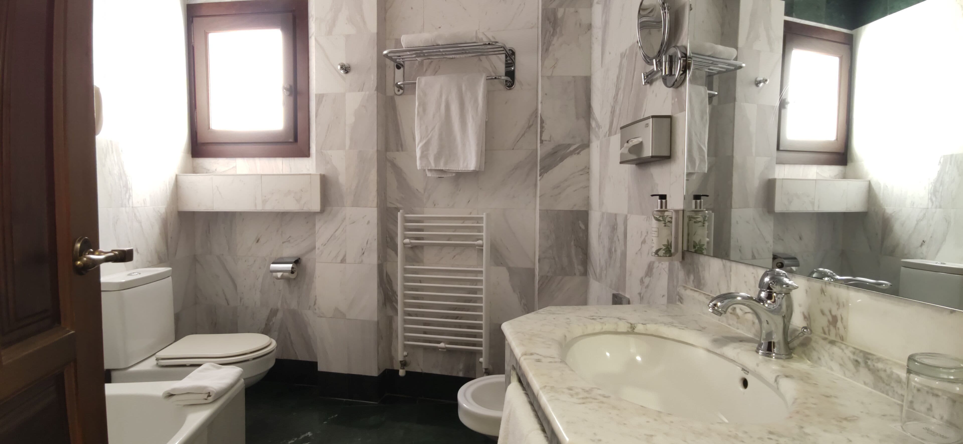 A bathroom with a toilet, sink, and mirror.