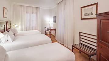 A hotel room with two beds, a desk, a chair, a TV, and a cabinet.