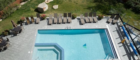 An outdoor swimming pool with lounge chairs and a small deck area.