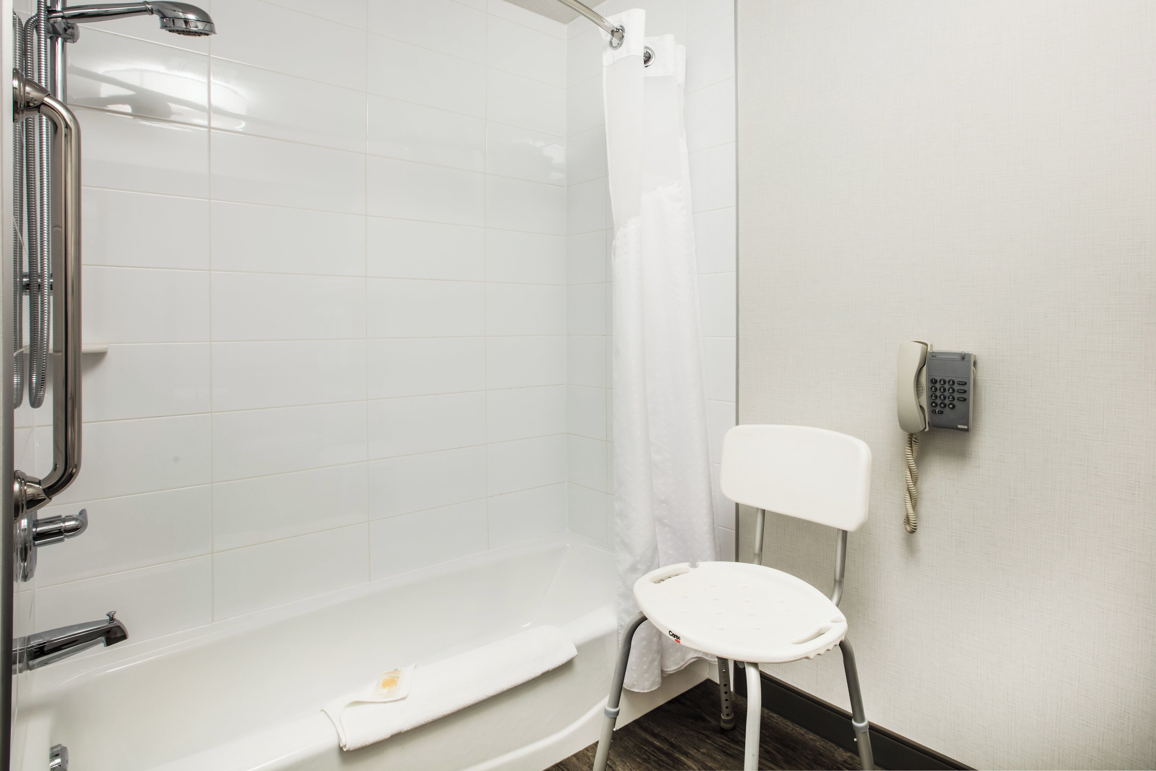 A bathroom with a shower, a toilet, and a telephone.