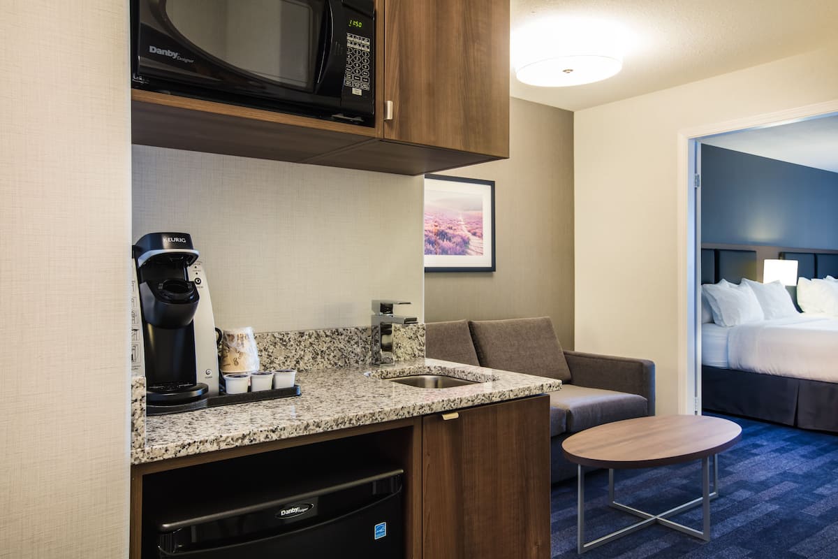 Habitación de hotel compacta con kitchenette, una cama, un pequeño espacio para sentarse y vistas al exterior.