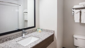 A bathroom with a granite countertop sink, a large mirror, and a towel rack with folded towels. - Holiday Inn & Suites Grande Prairie Conference Center by IHG (Grande Prairie)
