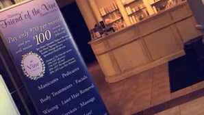 A salon interior with a reception desk, a chandelier, and a promotional sign advertising services like manicures, body treatments, and massages. - Holiday Inn & Suites Grande Prairie Conference Center by IHG (Grande Prairie)
