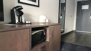 A kitchenette with a coffee maker, microwave, and a framed picture on the wall. - Holiday Inn & Suites Grande Prairie Conference Center by IHG (Grande Prairie)