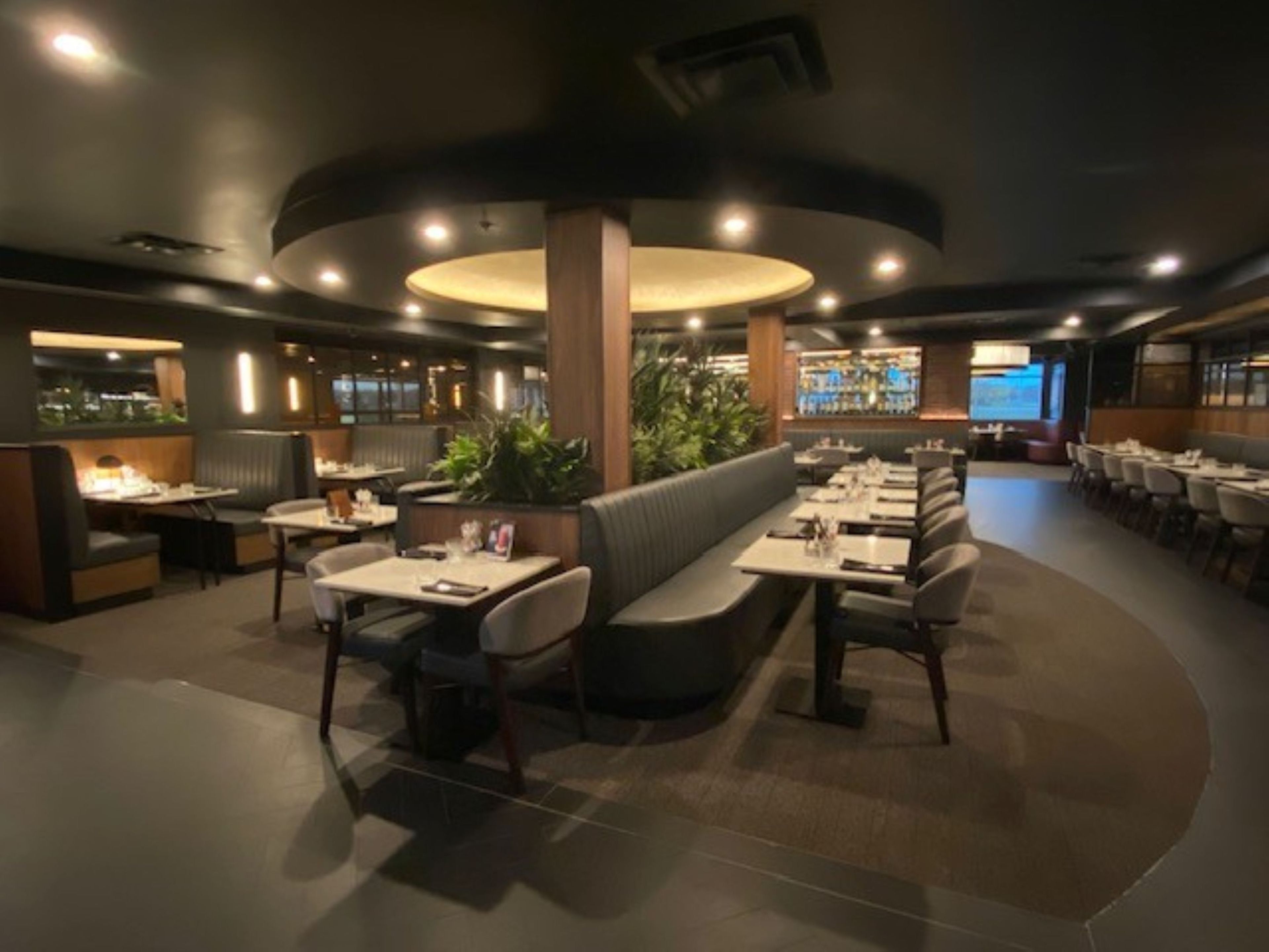 Un restaurante con cabinas, mesas y una zona de bar.