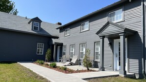 A two-story residential building with a covered patio and a small garden area. - Auberge Du Grand Lac (Magog)
