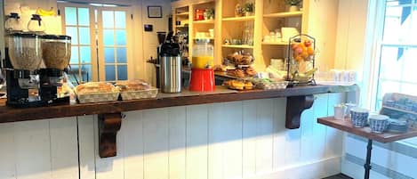 A breakfast bar with cereal, coffee, and fruit.