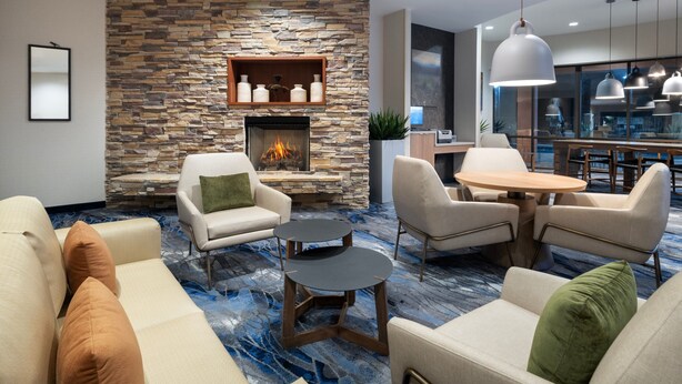 Una sala de estar moderna con chimenea de piedra, asientos cómodos y un comedor.