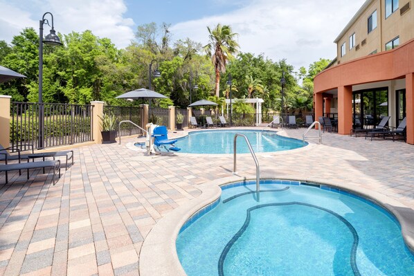 A pool area with lounge chairs, umbrellas, and a tiled deck. - Fairfield Inn & Suites Orlando Ocoee (Ocoee)