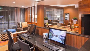 Un moderno vestíbulo de hotel con mostrador de recepción, computadora y zona de estar.