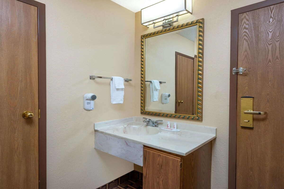 Une salle de bain avec un lavabo en marbre, un grand miroir et deux portes en bois.