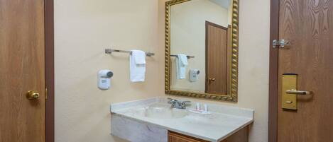 A bathroom with a sink, mirror, towel rack, and a door with a brass handle.